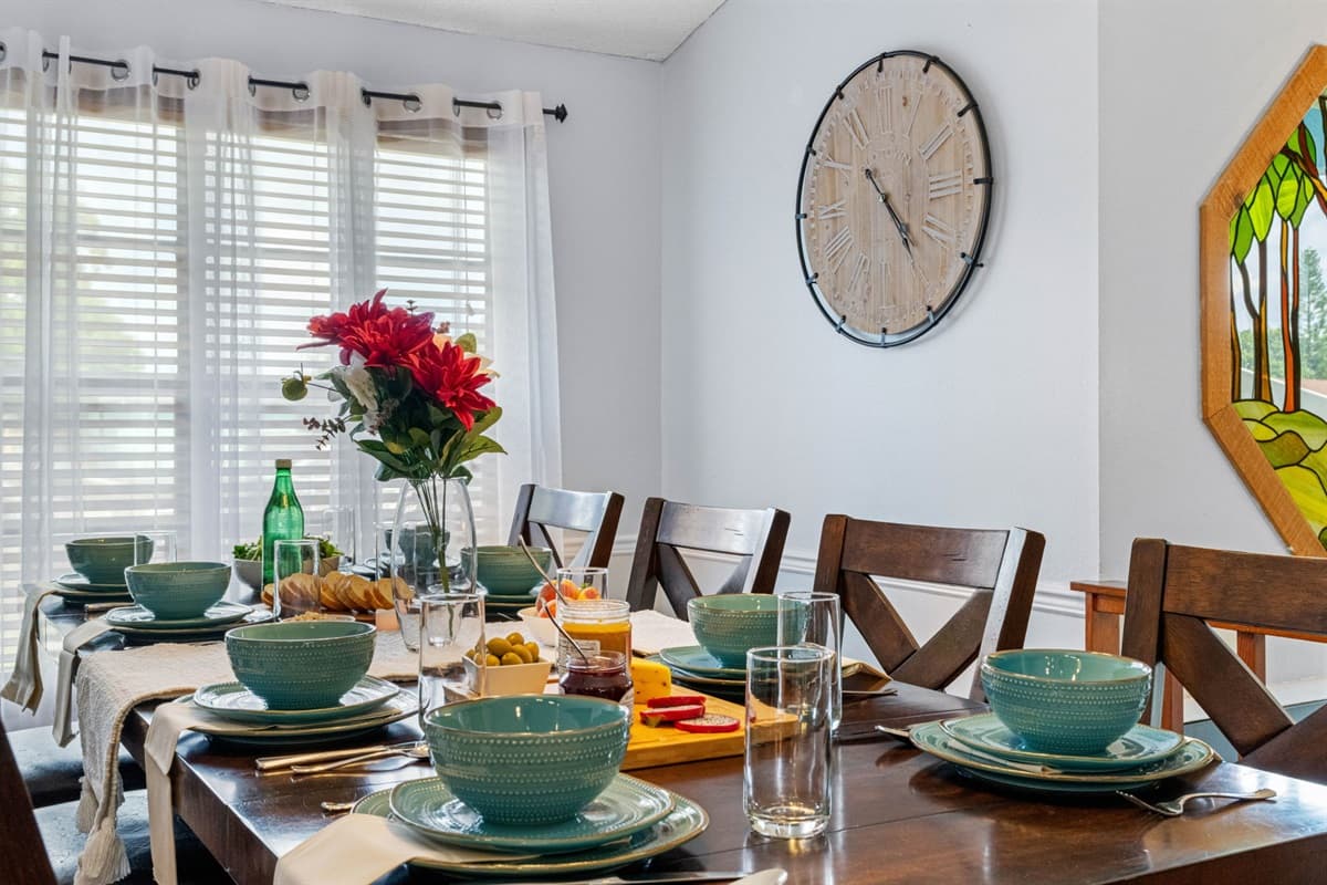 Enjoy comfort and style with this large, wood-finished dining table featuring cushioned chairs and beautiful natural lighting.