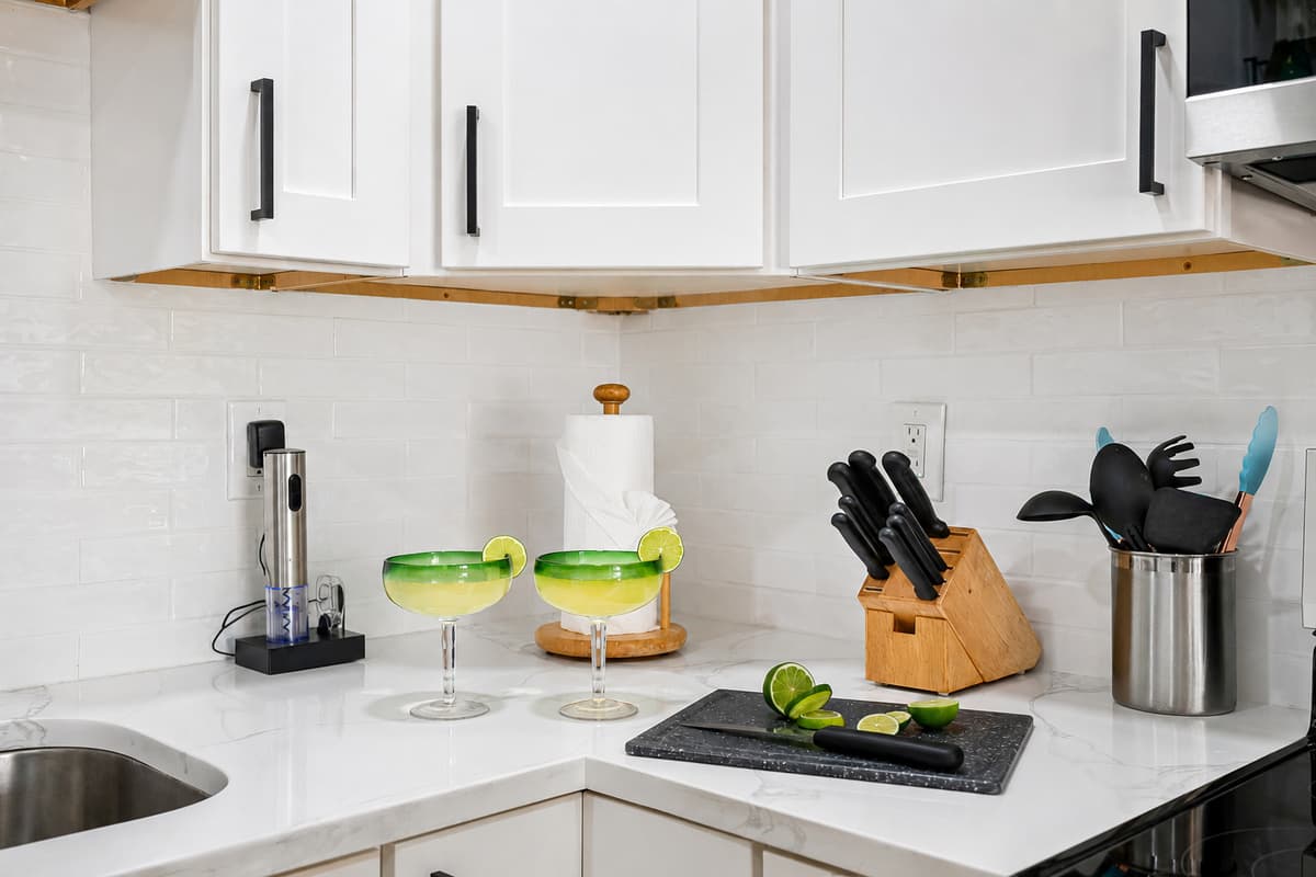 Featuring white shaker-style cabinets with bold black hardware, paired with gleaming marble-style countertops and a clean white subway tile backsplash, this kitchen is as visually stunning as it is functional.