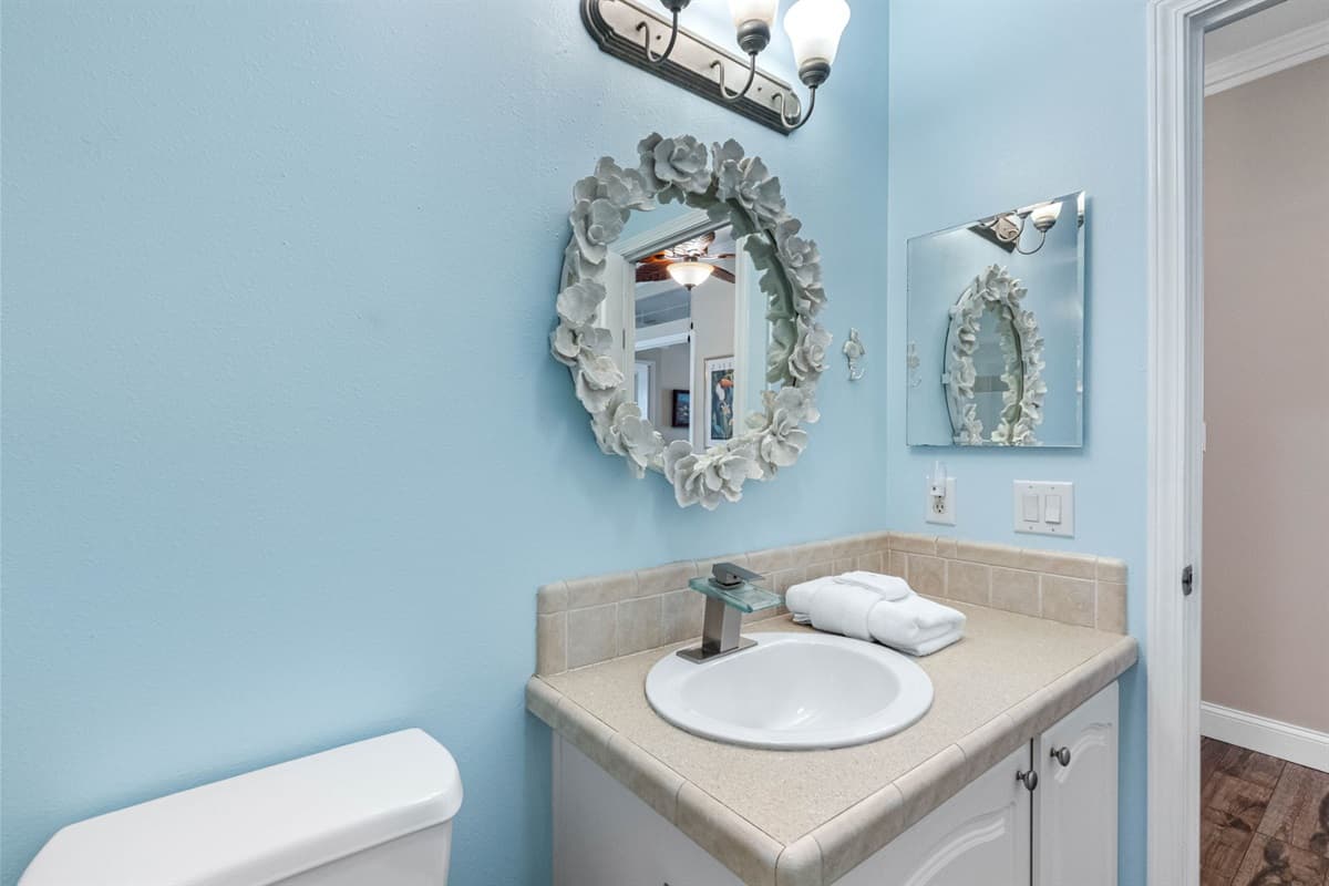 Bright and inviting, this bathroom includes a spacious tiled shower with sliding glass doors, a classic white vanity, and elegant lighting that adds warmth to the space.