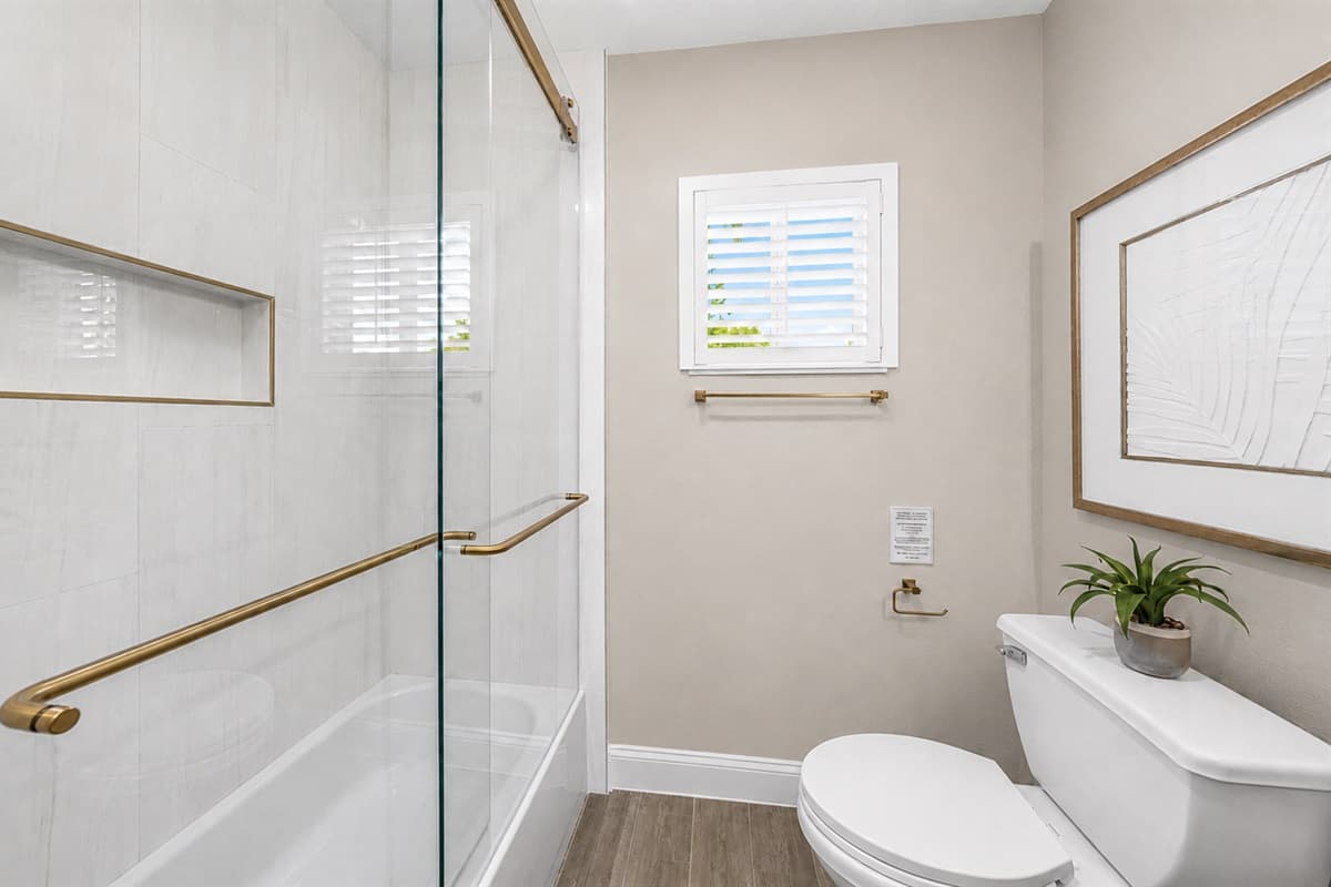 Clean and modern bathroom featuring a walk-in shower with elegant gold accents and bright finishes.