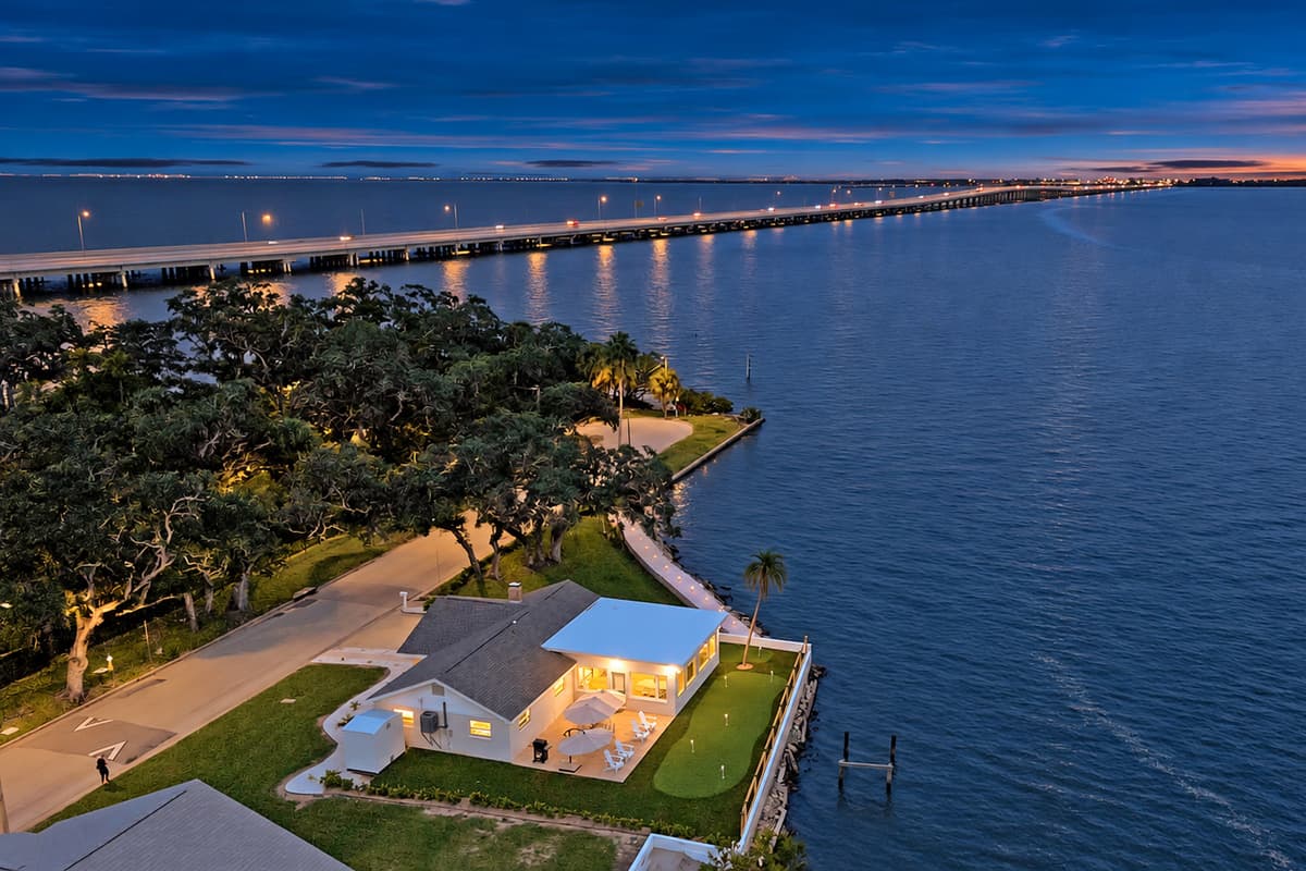 The bay, the bridge and your house. At twilight the bridge lights stretch across the water while the home glows on its own waterfront corner. A view few rentals can match.