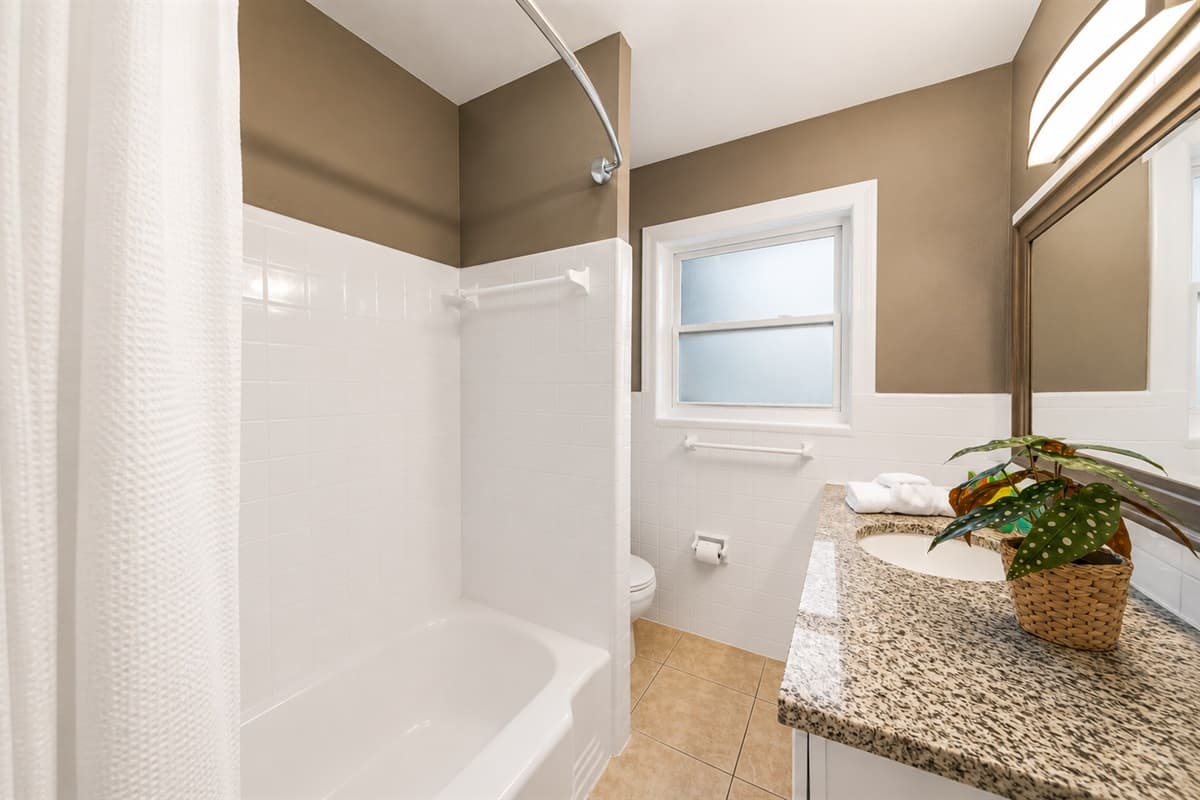 Bright guest bathroom featuring a full bathtub and shower setup with plenty of natural light.