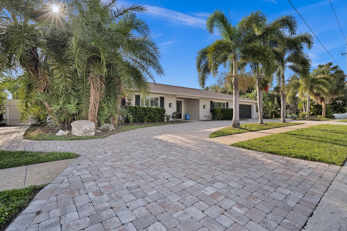 Towering palms and a paver driveway welcome guests to a beautifully landscaped single-story home from the very first glance