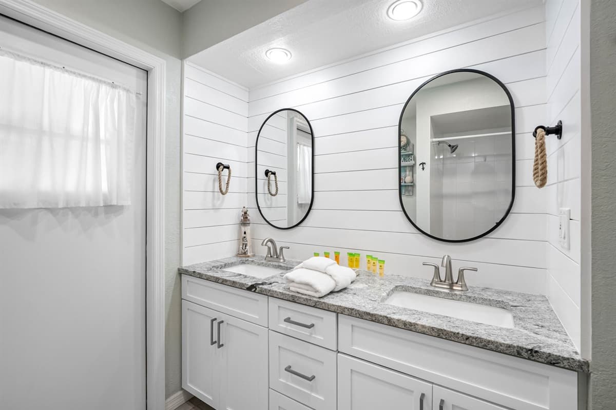 Dual mirrors, bright lighting, and clean finishes create a refreshing space to unwind.