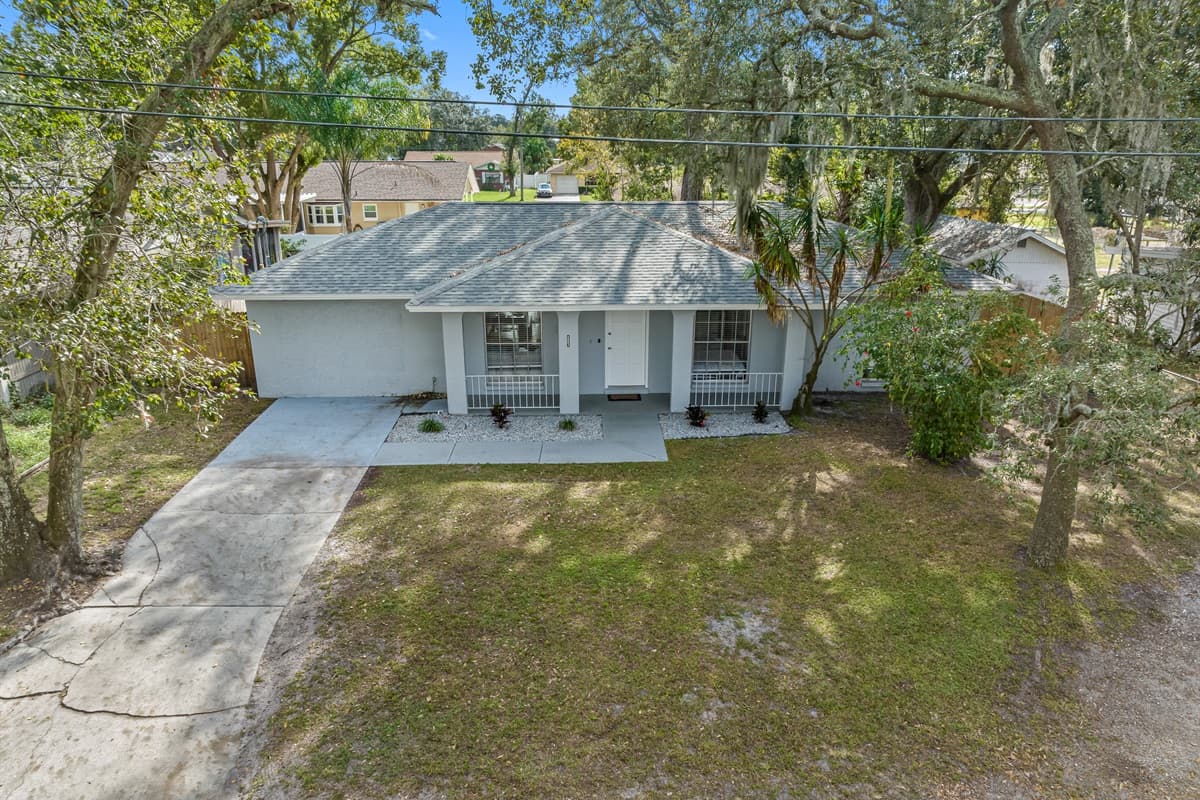 Aerial front view of our beautiful house showcasing our spacious driveway and parking. The property is surrounded by trees and is fully fenced. If you are interested in this property, send us an inquiry now!