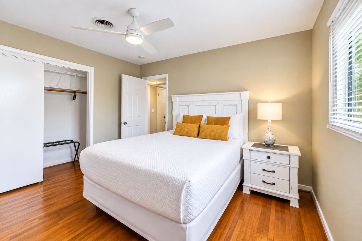 Cozy guest bedroom featuring a comfortable queen bed, soft lighting, and warm wood flooring.