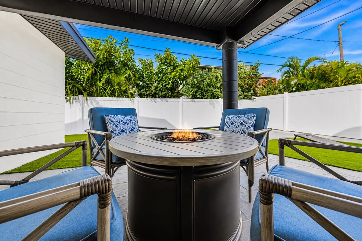 Covered outdoor lounge area featuring a relaxing fire pit table and comfortable seating.