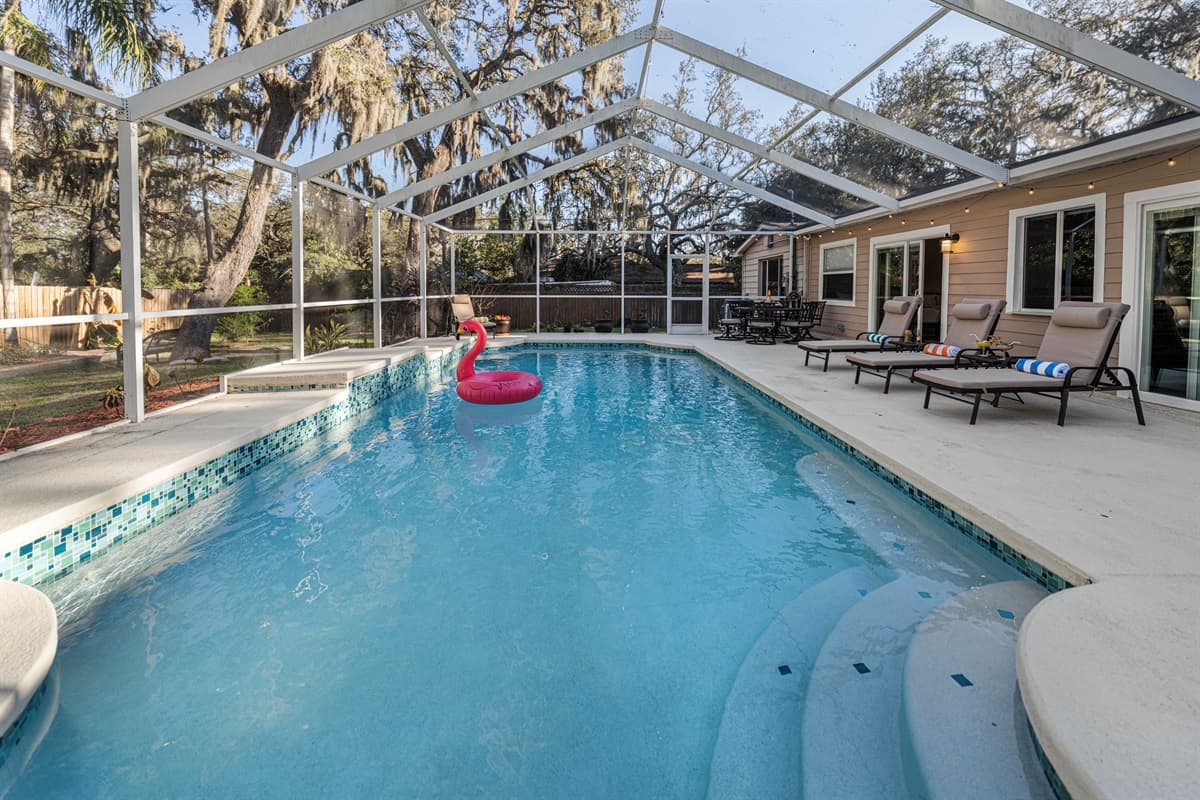 A beautiful panoramic view of the private screened-in pool, surrounded by tranquil wooded scenery that provides both privacy and a relaxing retreat atmosphere.