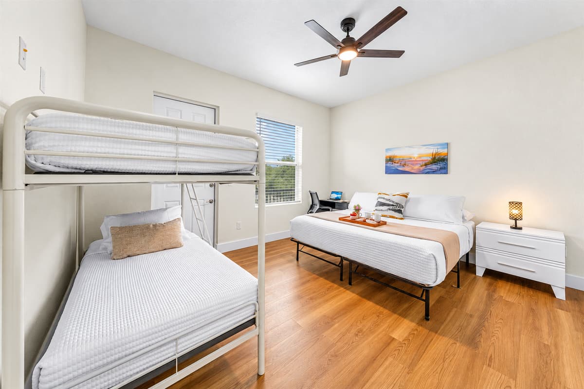 Sleeps four in one room, comfortably. A king bed plus a bunk bed means Bedroom 3 alone fits four guests, with a desk, bedside lamp, and direct balcony access. Ideal for families who want the kids close, but not in their bed.