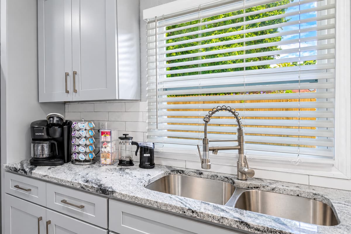 A sunny sink with a view. Double stainless sink under a big window, with the coffee station right beside it. Cleanup goes fast with the dishwasher just below.