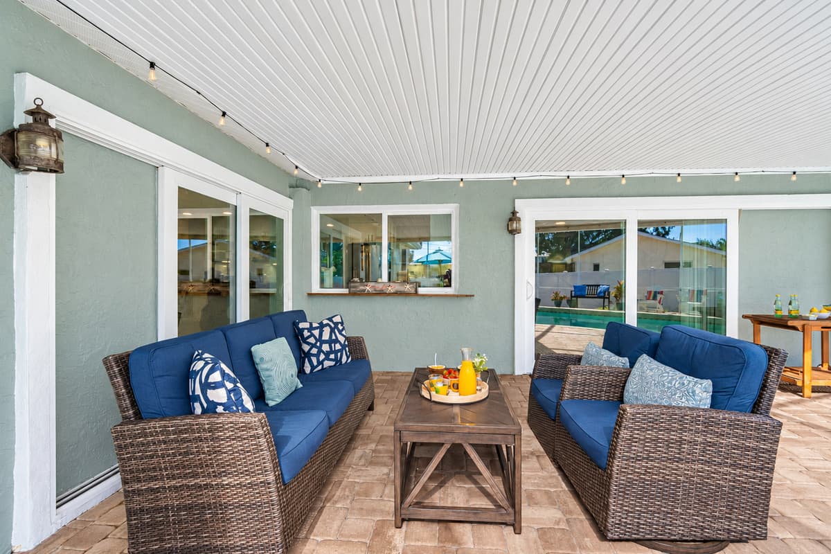 Enjoy the best of indoor-outdoor living with this screened pool and cozy lounge area, surrounded by tropical plants and twinkling string lights.