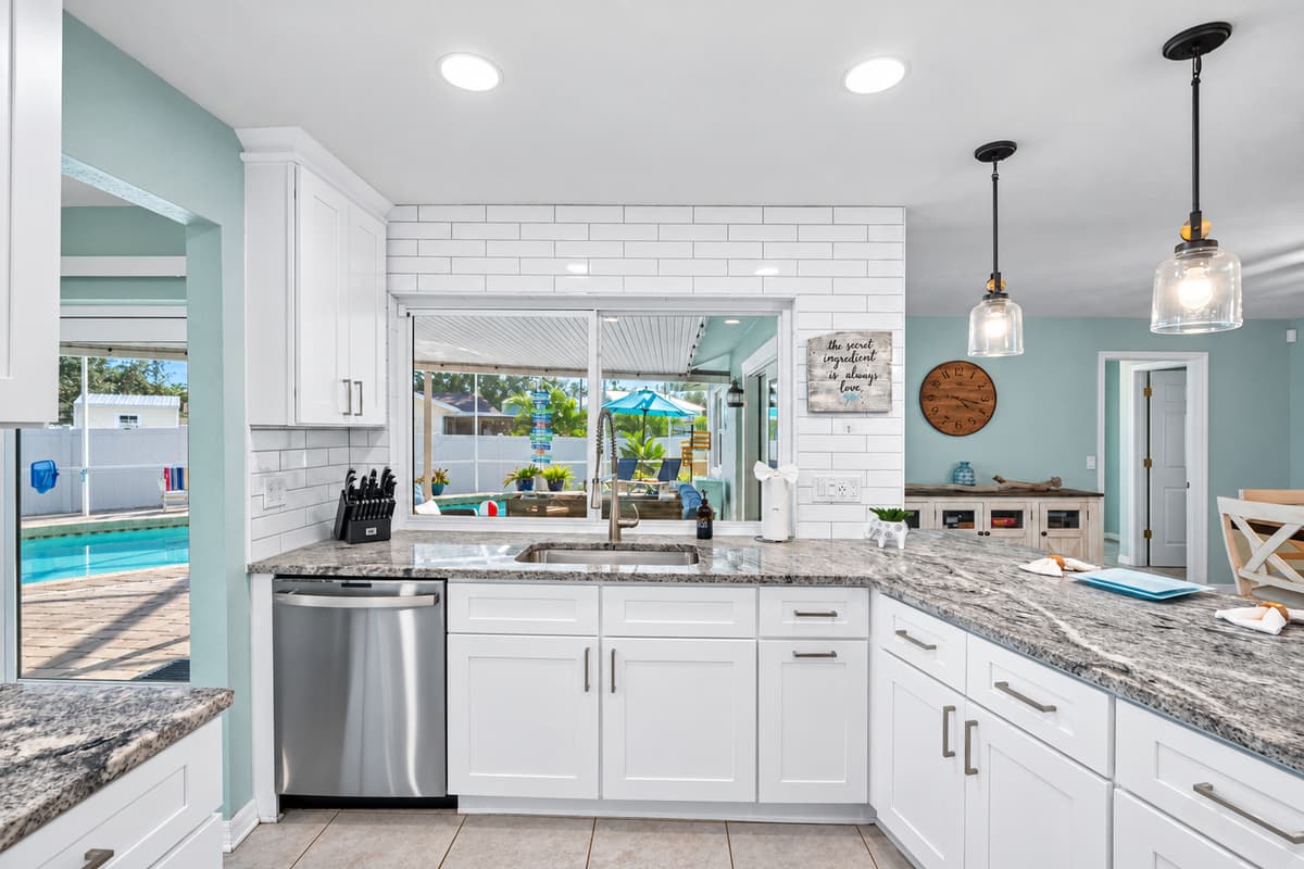 Sleek white cabinetry, stainless steel appliances, and granite countertops create a bright, elegant space for cooking and gathering.