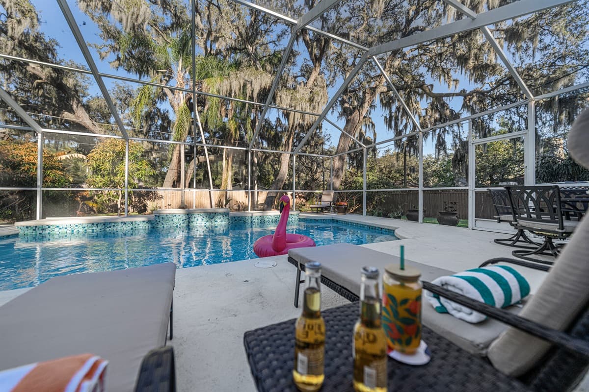 Unwind poolside with shaded lounge seating, creating the ultimate vacation atmosphere under the screened enclosure.