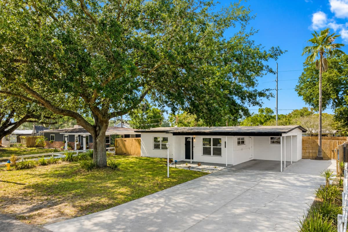 The front yard is adorned with greenery plants, and trees, creating a warm and welcoming atmosphere.