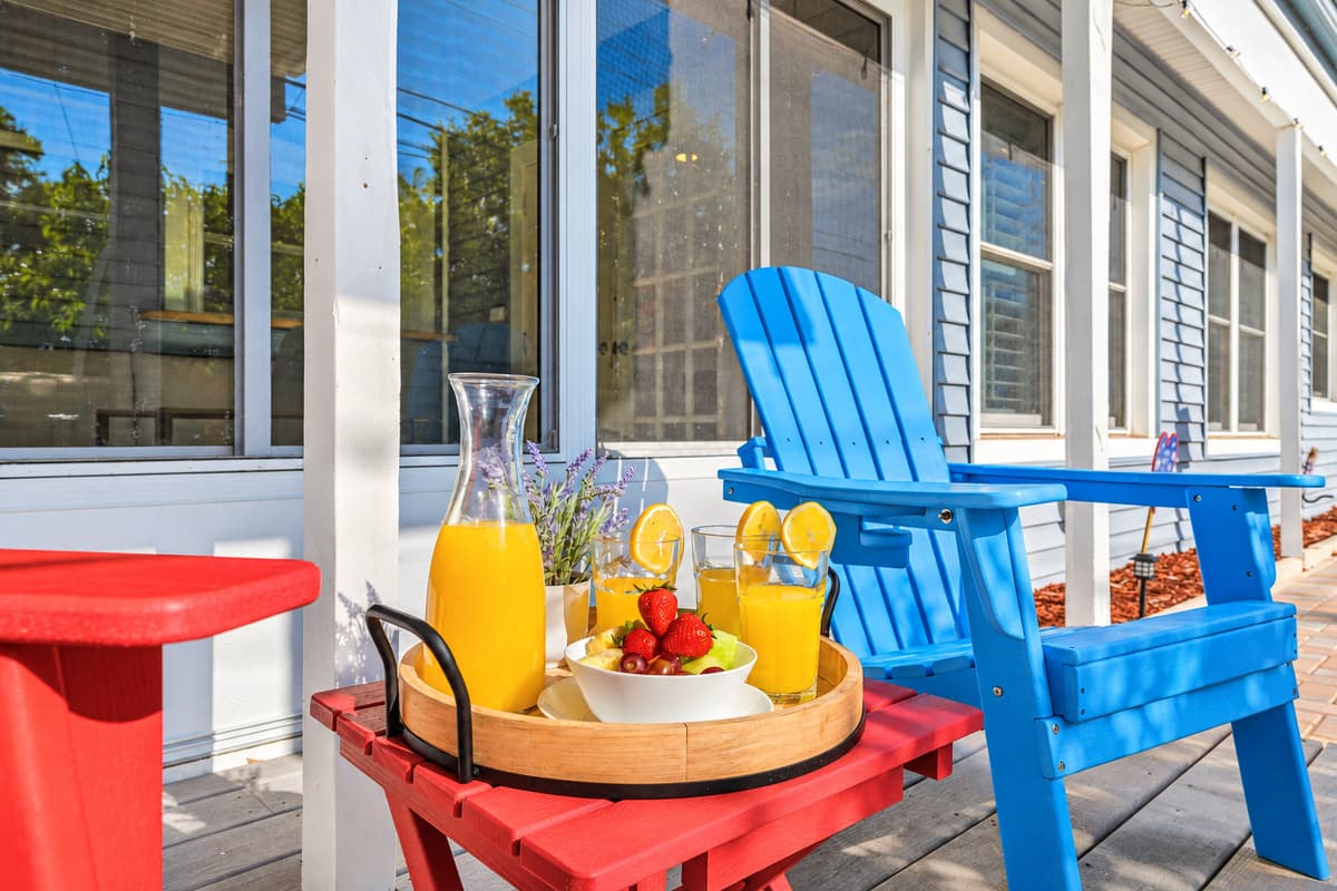 Outdoor seating area with colorful Adirondack chairs and a cozy setup—perfect for relaxing poolside 
Food and drinks shown are for staging purposes only and are not included.