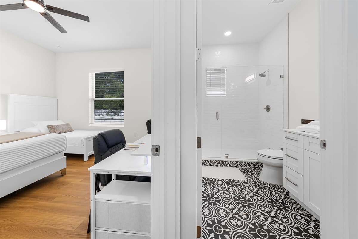 Modern bathroom featuring a sleek glass walk-in shower, stylish patterned tile flooring, and a clean, bright vanity space.