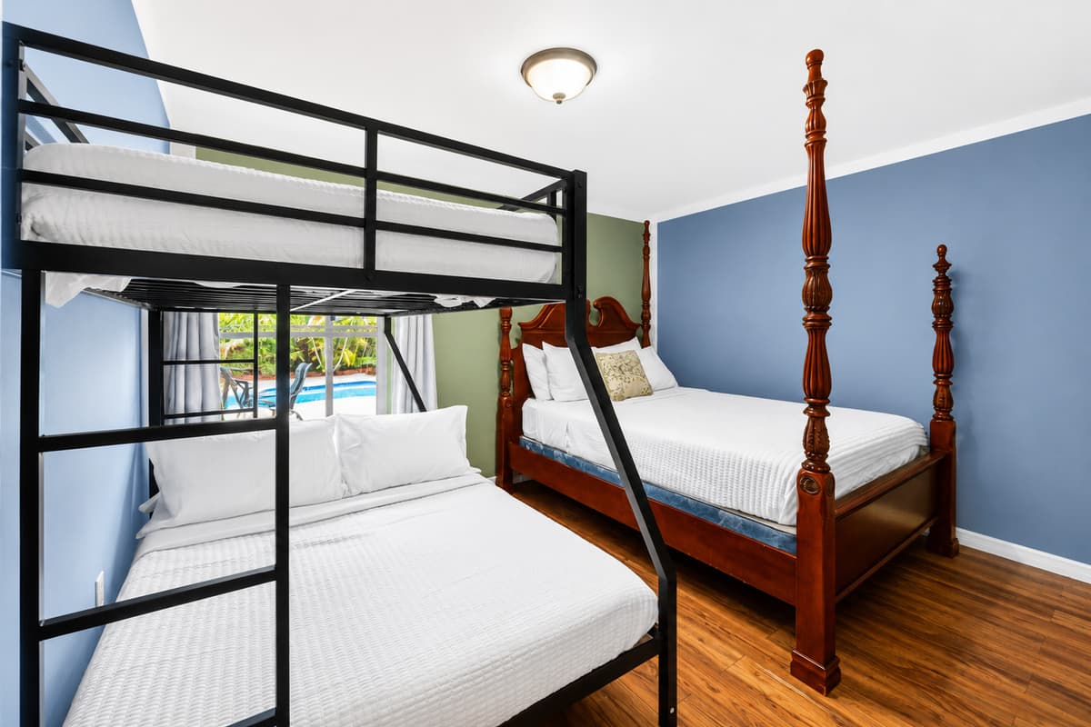 Comfortable room offering a queen bed and bunk bed setup with pool views.