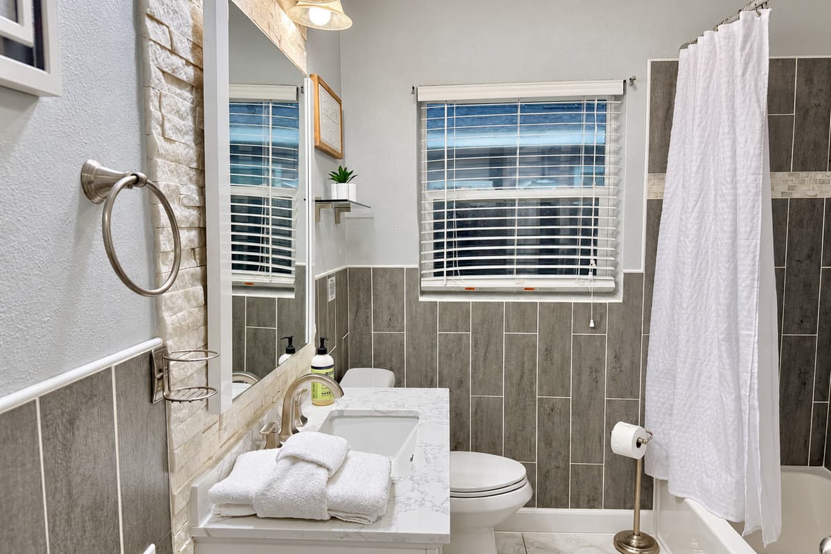 With its large mirror, natural light, and neutral palette, this bathroom offers a refreshing start and relaxing end to your day.