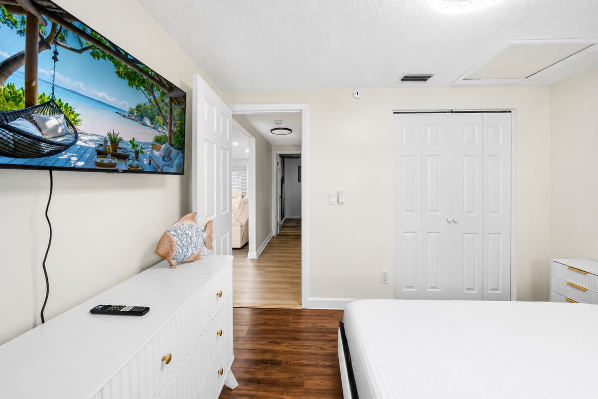 Bright and welcoming bedroom with Smart TV, dresser storage, and easy access to the rest of the home.