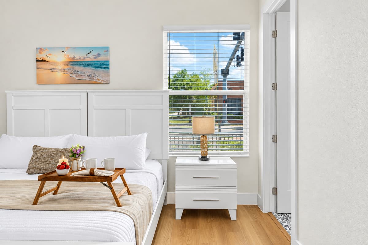 Comfortable bedroom with large window, natural light, and cozy décor.