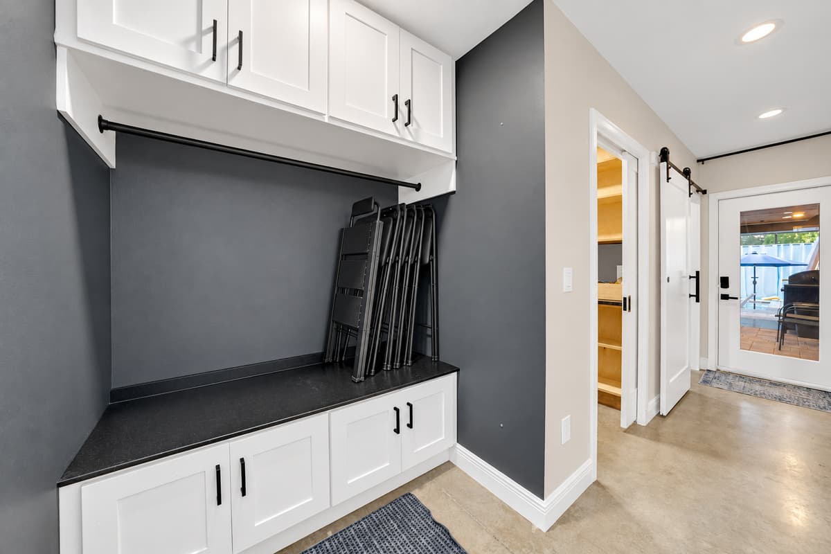 Drop the beach bags here, not in the bedroom. Built-in bench with hooks above and drawers below — the landing spot for towels, sandals and everything that comes back wet from the pool.