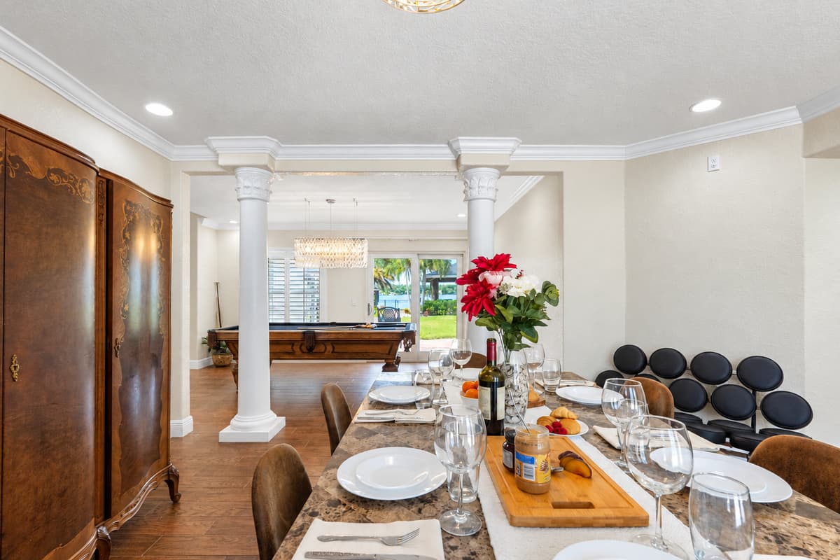 A blend of traditional elements—like decorative columns and antique-style cabinet—with modern finishes creates a versatile dining room style.