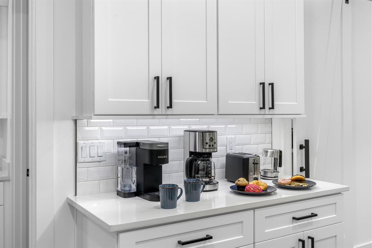 White-painted cabinetry lines the kitchen, adding a fresh, bright look that beautifully complements the open design.