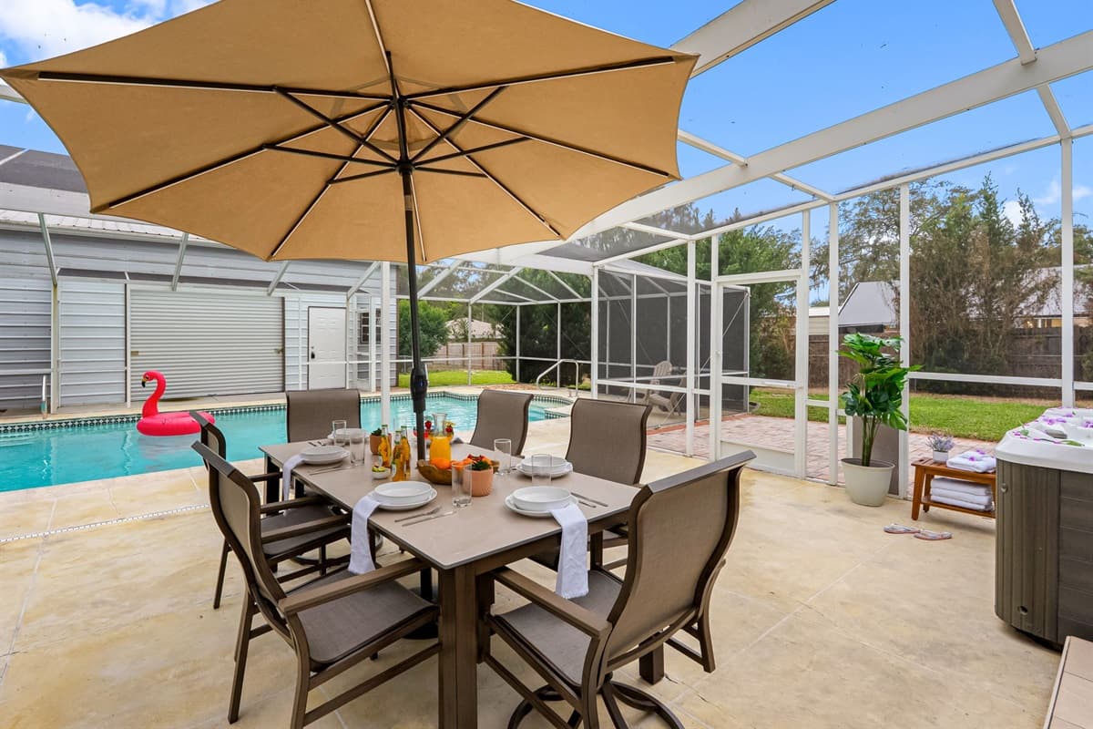 Dine al fresco in this spacious screened patio, featuring a large outdoor dining table and relaxing poolside views.