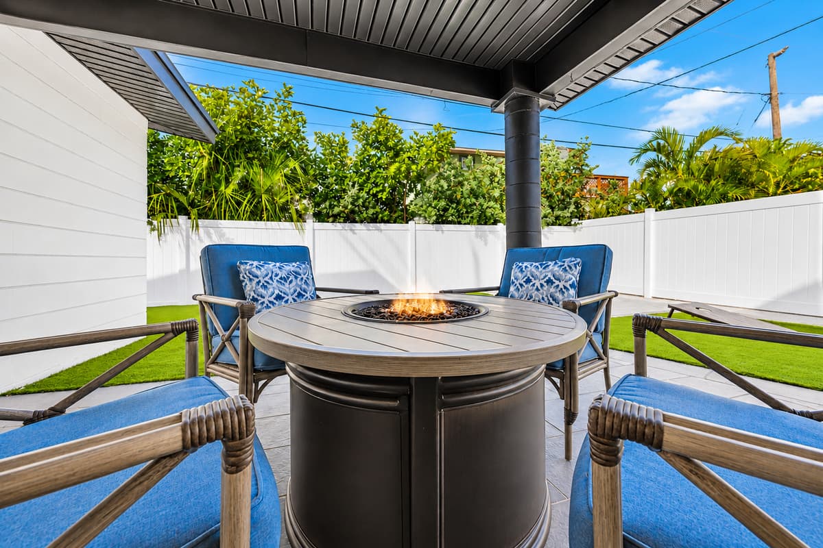 Covered outdoor lounge area featuring a relaxing fire pit table and comfortable seating.