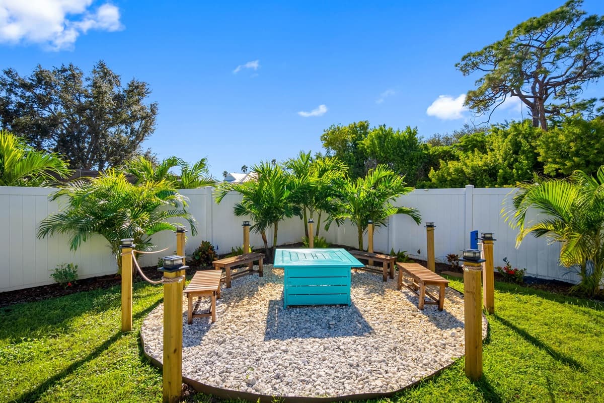Gather around the vibrant turquoise firepit surrounded by tropical landscaping—ideal for evening drinks and conversation under the stars.