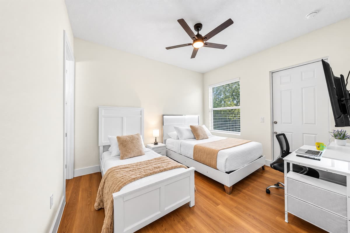 Stream in bed after a long day out. Queen bed, twin bed, wall-mounted Smart TV, and a desk: this room handles movie nights, work calls, and deep sleep. A ceiling fan keeps the Florida heat in check all night.