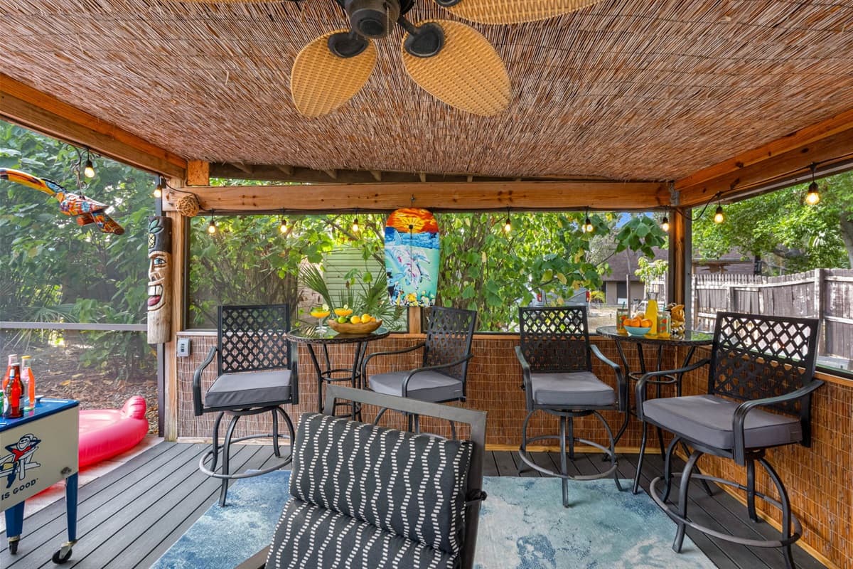 This colorful patio is packed with personality—featuring playful tiki carvings, island-themed décor, a bar setup, and cozy seating.