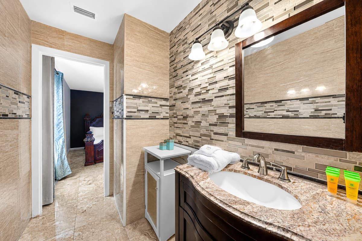 Modern bathroom featuring a granite vanity, spacious mirror, and stylish finishes.