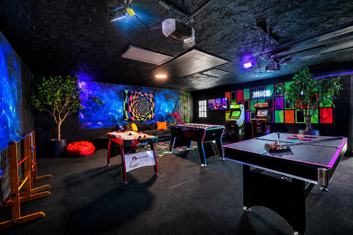 Pool table, ping pong, arcade, and a sofa for whoever's out — the whole room is one long turn-taking machine.