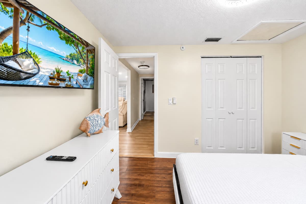 Bright and welcoming bedroom with Smart TV, dresser storage, and easy access to the rest of the home.