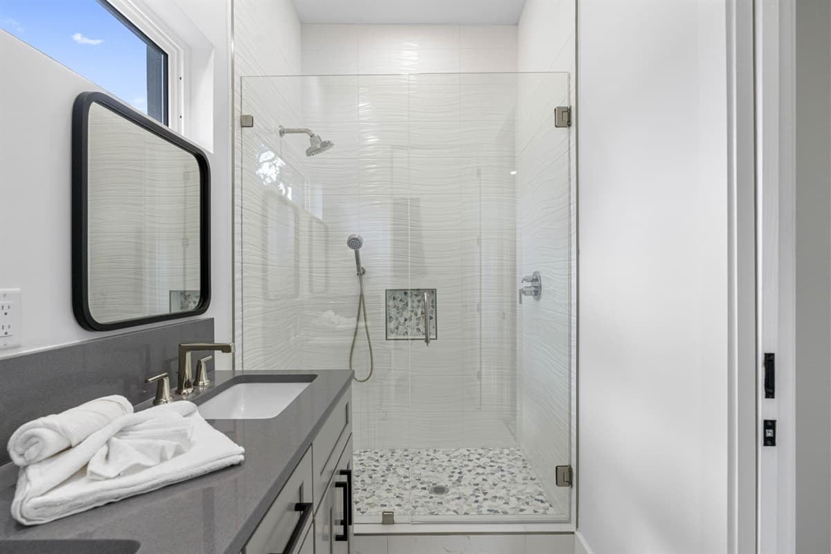 The ensuite bathroom is equipped with a double sink vanity and a spacious walk-in shower, providing a spa-like experience to refresh and rejuvenate.