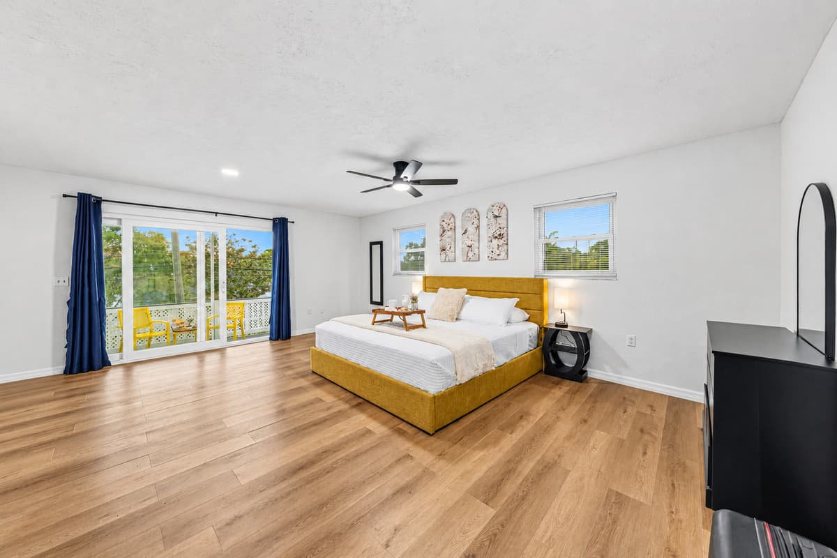 Bright and airy bedroom with king bed and sliding glass doors leading to outdoor seating 