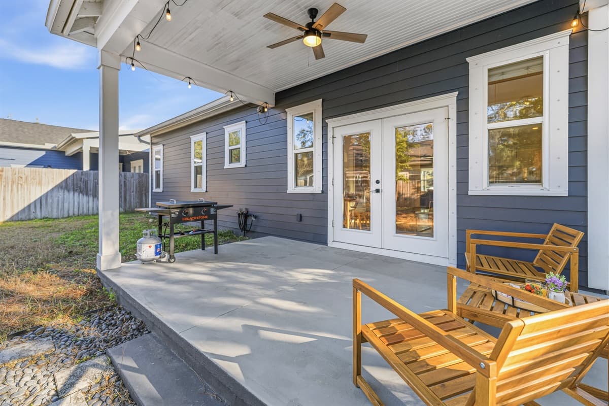 Another view of the gorgeous covered back patio — warm wood lounge chairs, ceiling fan, and French doors leading inside. The perfect spot to sip your morning coffee or wind down after exploring everything Seminole Heights has to offer.