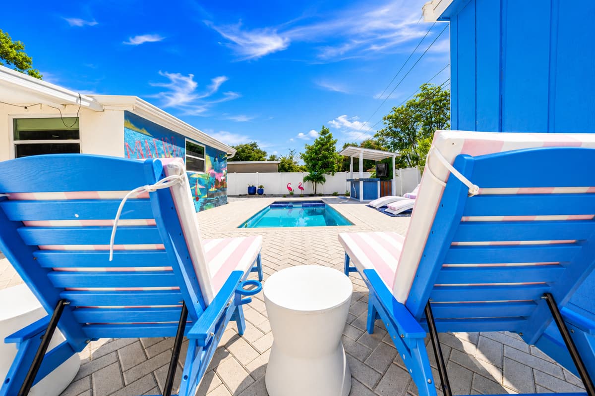 Poolside lounge area featuring comfortable sun chairs, side table, and views across the entire outdoor entertainment space.
