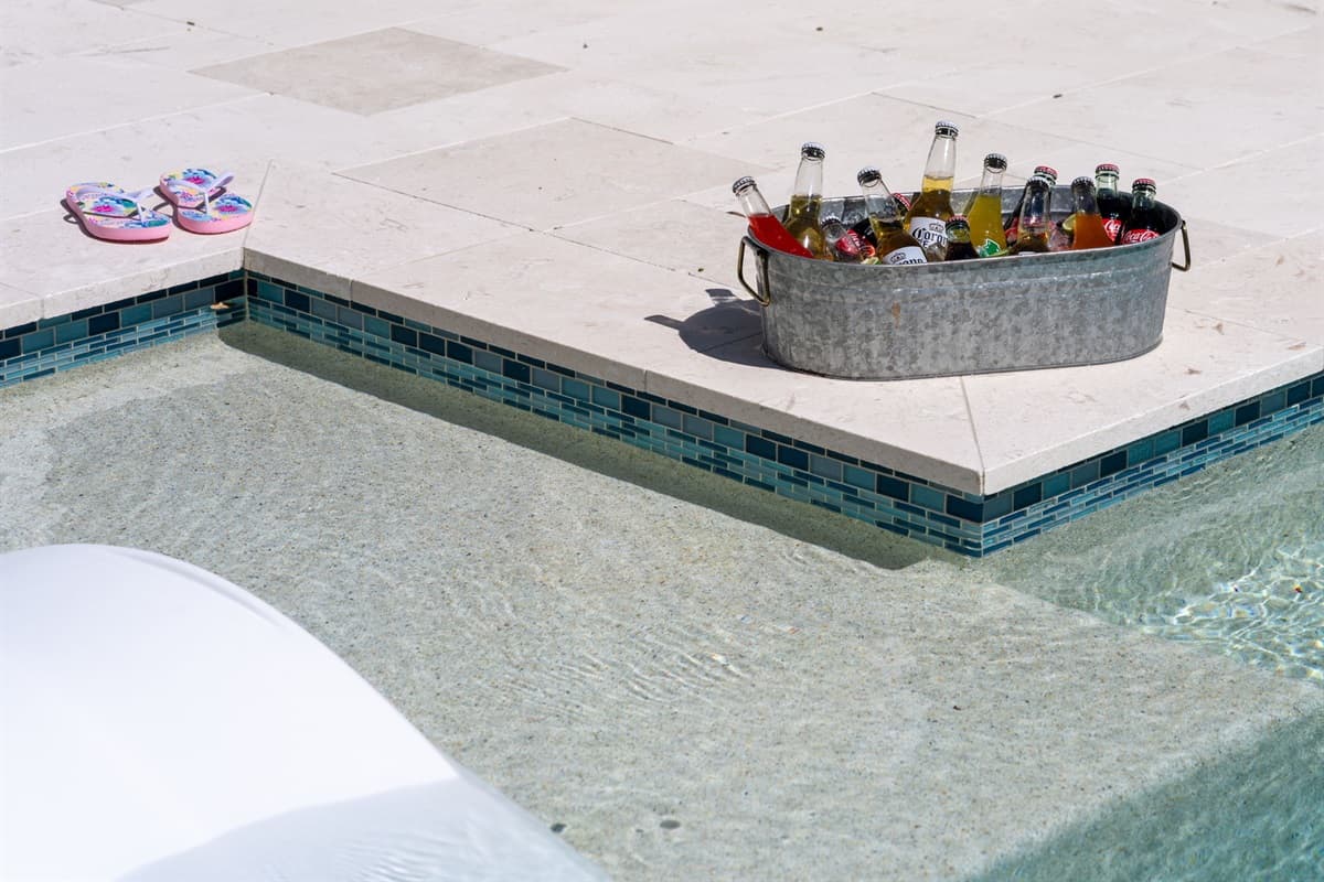 White stone tile, minimalist landscaping, and crisp design make this pool area pop.