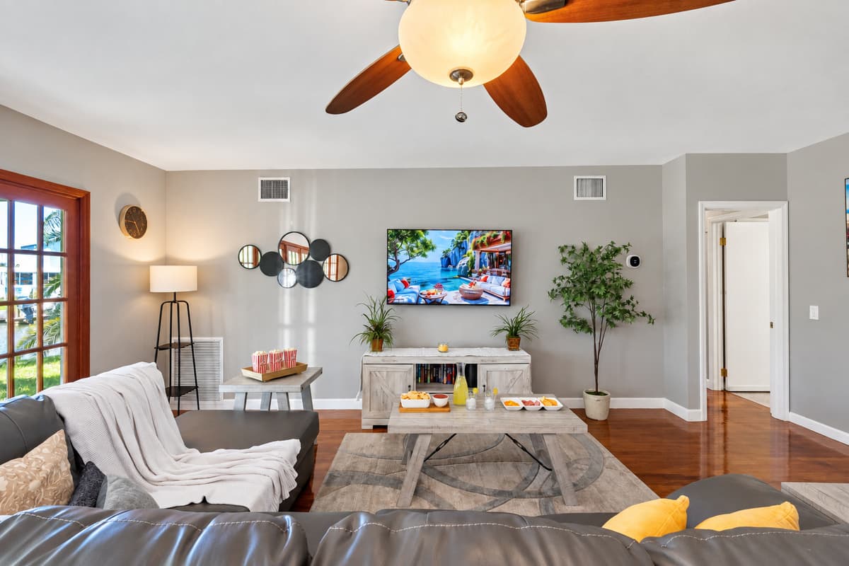 Outfitted with a large mounted TV, spacious sectional seating, and snack-ready tables, this living room is perfect for family movie nights or casual entertaining.