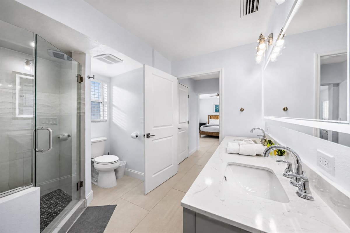 Bright and spacious modern bathroom featuring a walk-in glass shower and large vanity area.