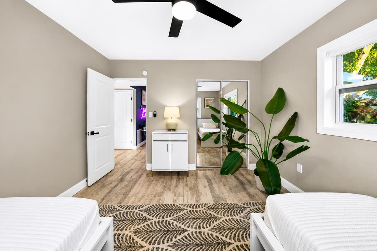 Twin bedroom viewed from the bedside, highlighting ample floor space, dresser storage, and modern furnishings.