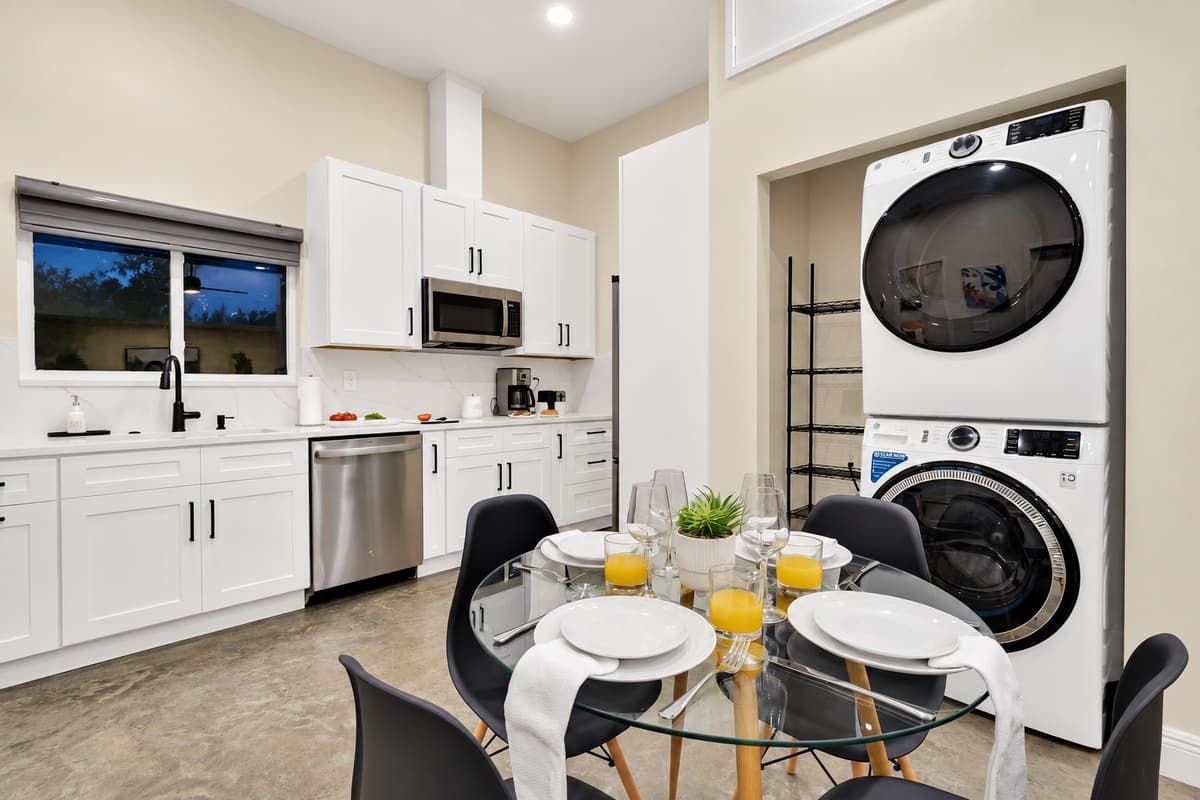 Cook, eat and do laundry without leaving the wing. Dishwasher, microwave, stacked washer and dryer, and a table set for four — everything a family needs to run its own day inside a much larger house.