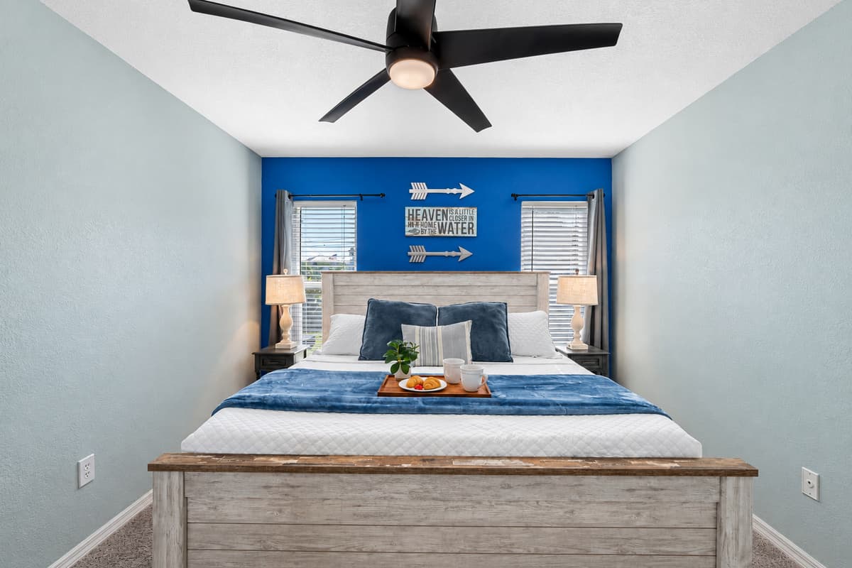 A spacious bedroom with a king bed, modern ceiling fan, and cozy carpet flooring for extra comfort.