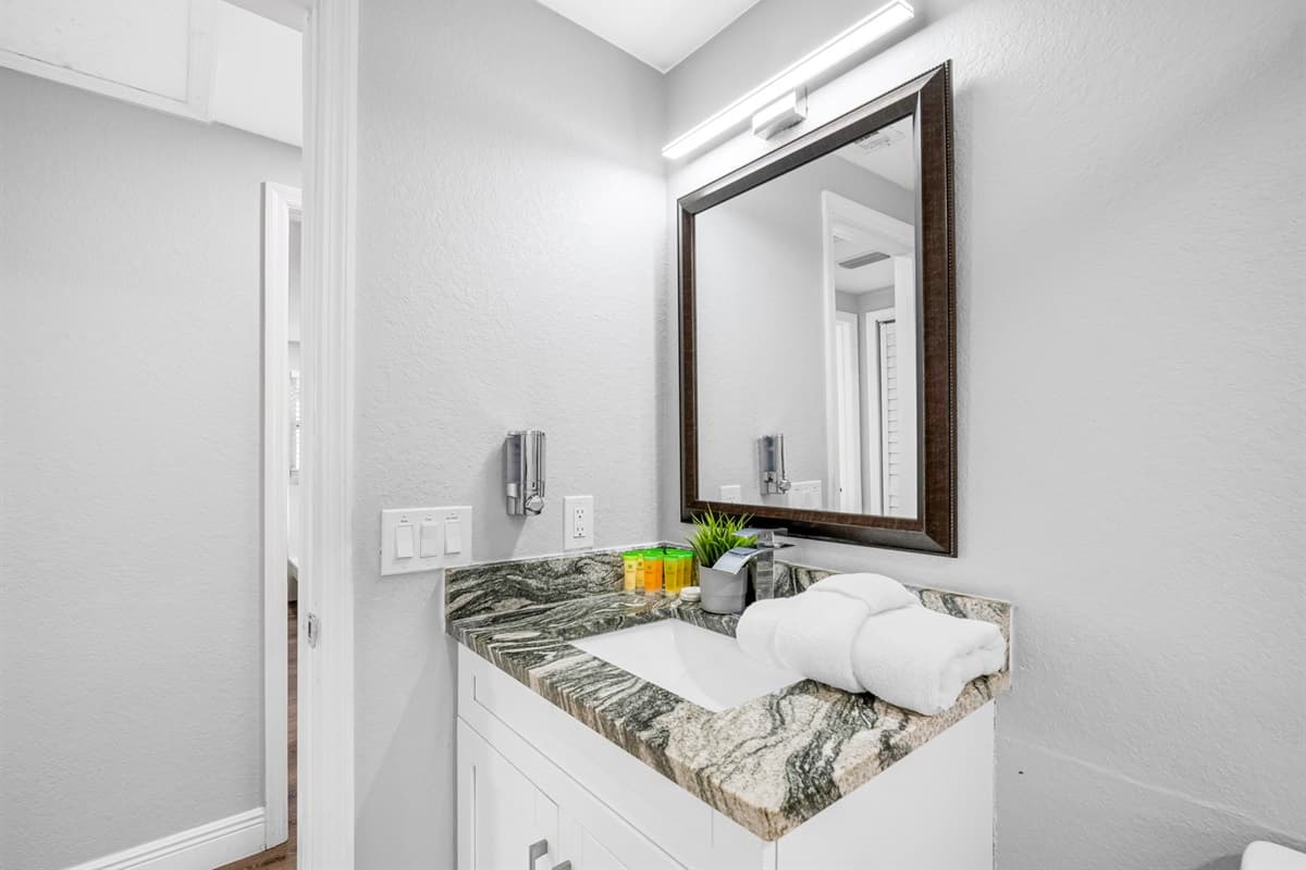 White tile walls and a granite countertop create a fresh, luxurious feel.