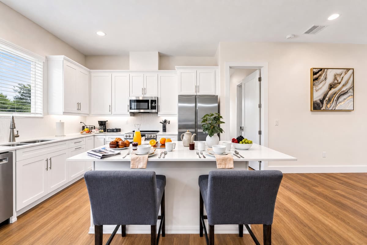 The island is the centerpiece: seating for two, room for four to cook, and open sightlines to the rest of the floor.