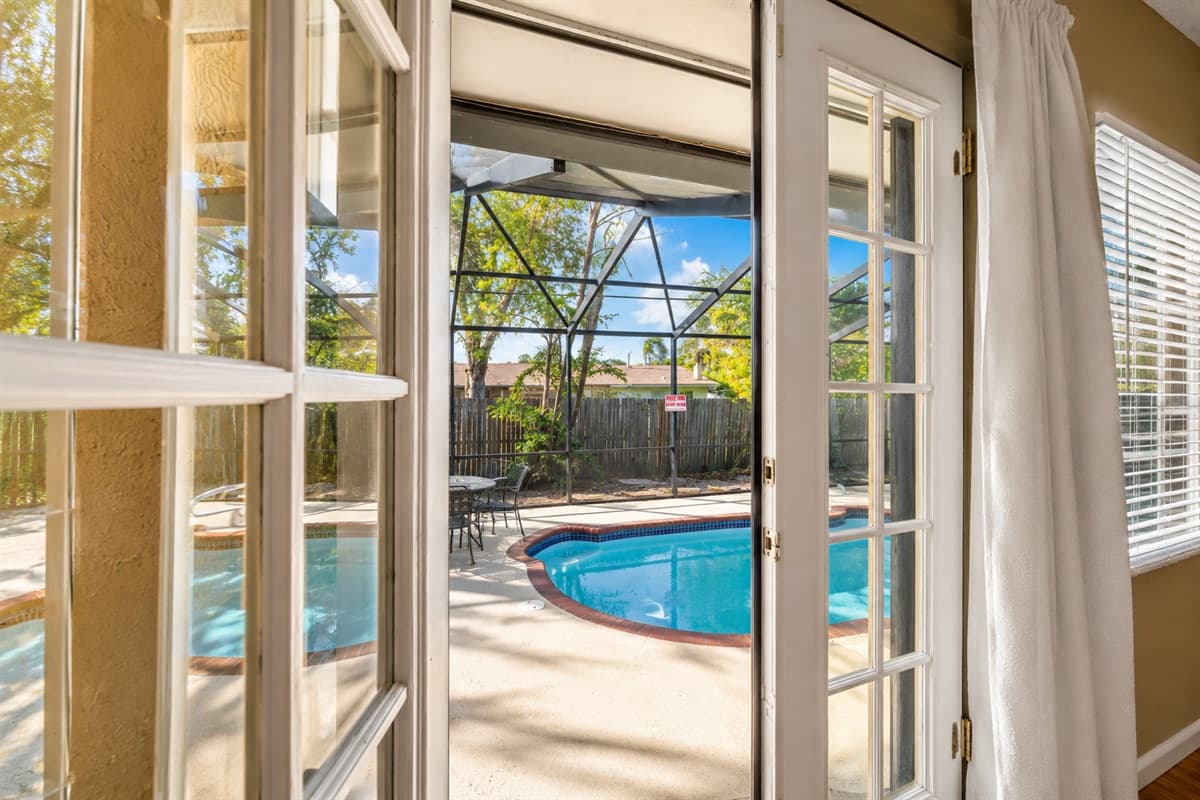 Bright interior view with French doors leading directly to the screened pool and patio area.
