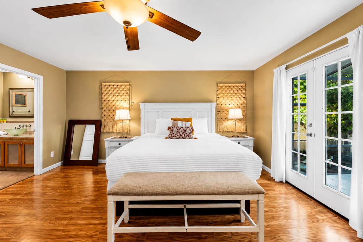 Spacious primary bedroom featuring a king bed, elegant décor, and private French door access to the outdoor area.