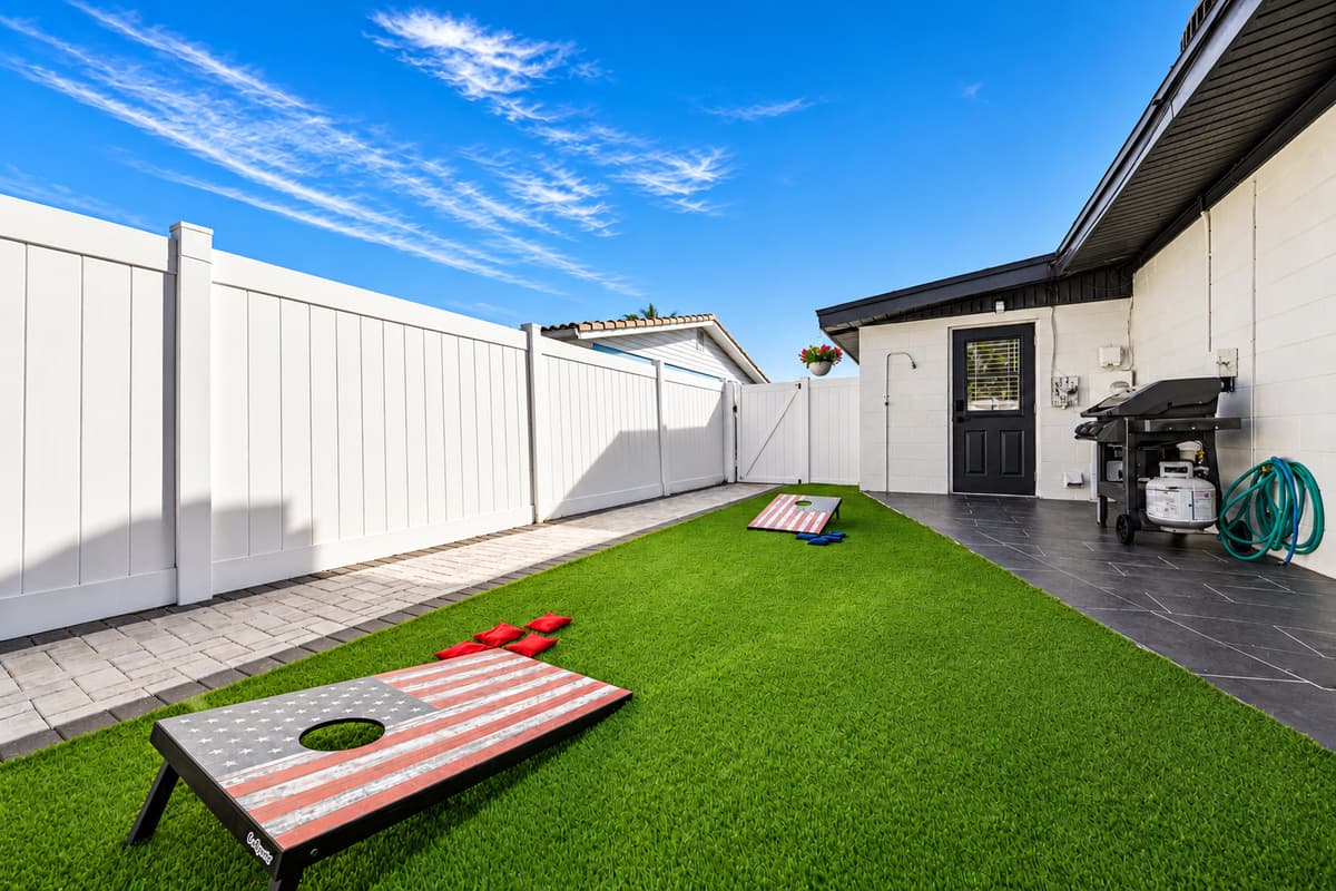 Grill is here. Cornhole is here. Nothing else needed. Fenced turf yard with room to run, a grill ready to fire, and games already set up outside. Step through the door and the afternoon plans itself.